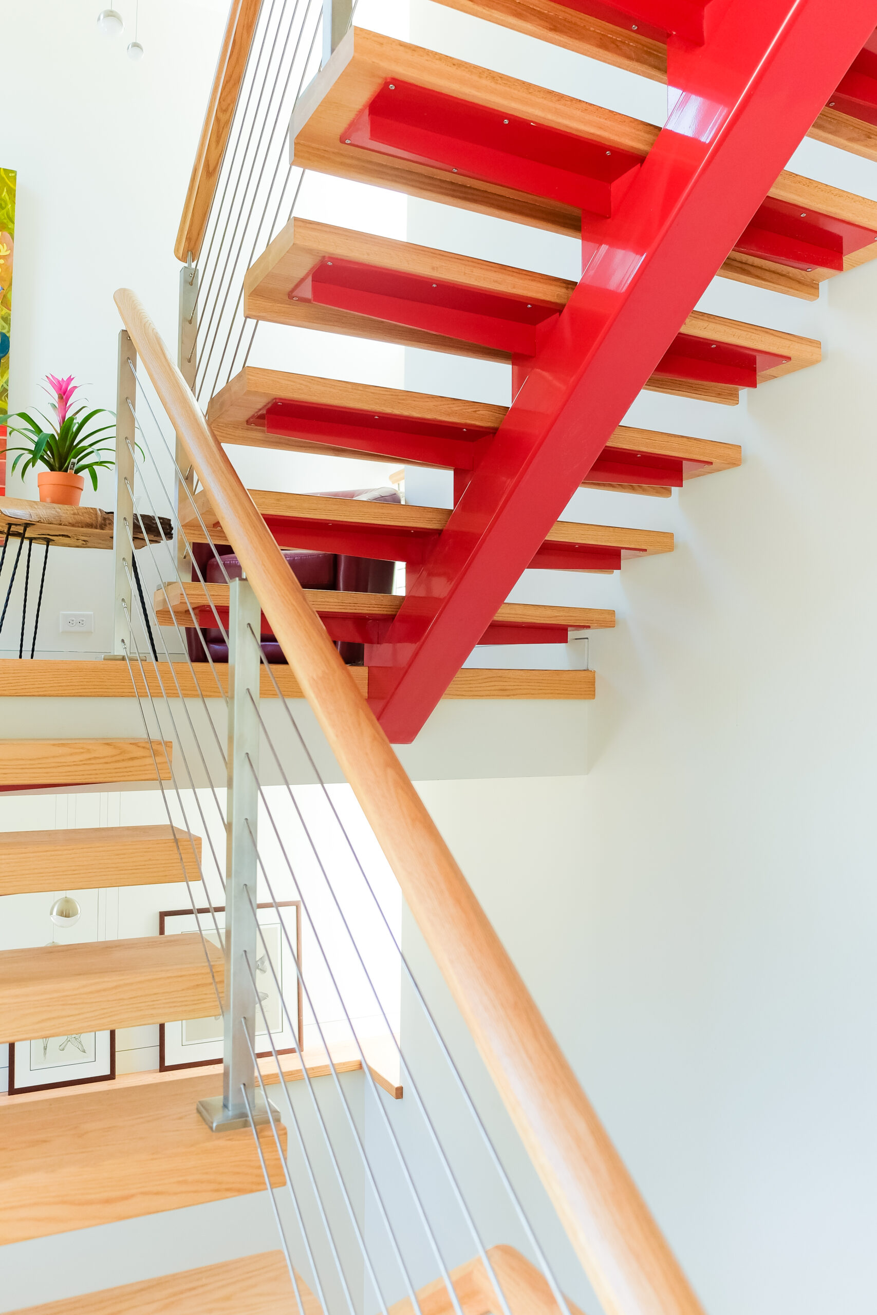 wood open riser stairs with single red monobeam and cable railing system close up view